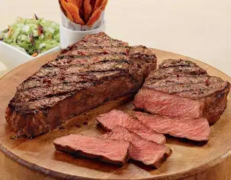 A succulent steak and fries served on a wooden cutting board, perfect for meat lovers.