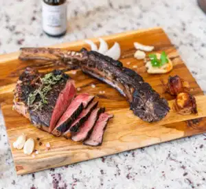 A steak sitting atop a wooden cutting board, ready to be tenderized with a Blade Meat Tenderizer.