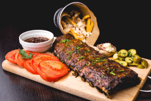 Ribs and fries served on a wooden cutting board.