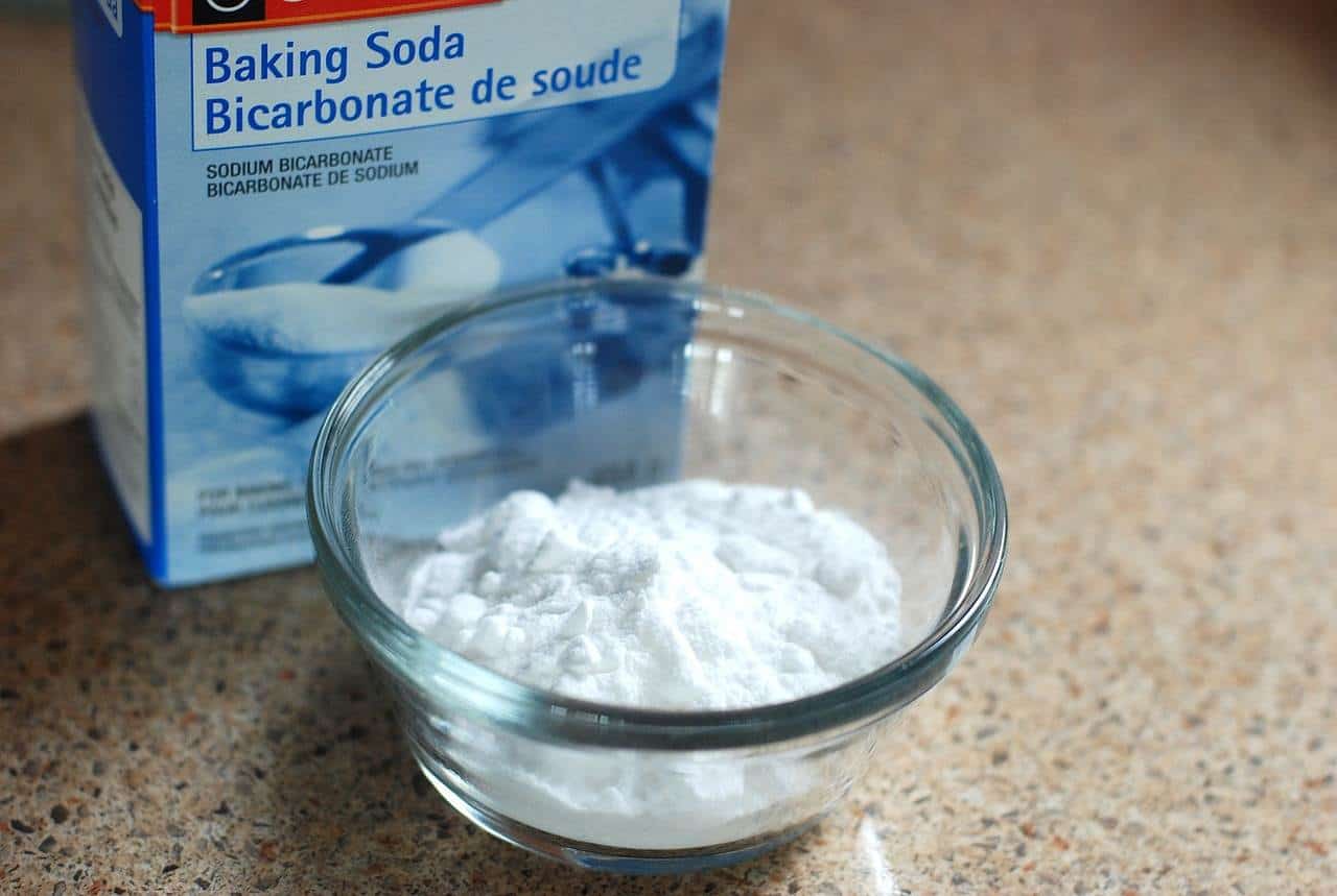 A bowl of baking soda next to a box of baking soda.