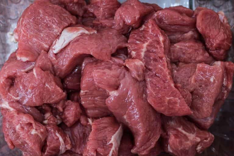 A pile of raw, red beef pieces stacked together, ready to be transformed into a culinary delight with the help of XSpecial Meat Tenderizer.